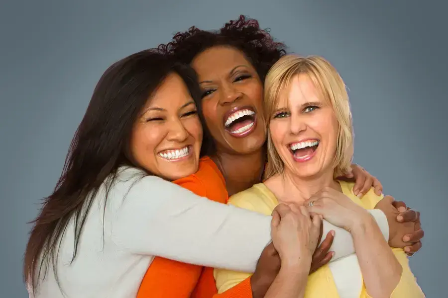 Three joyful women embracing in a group hug, laughing and smiling after receiving Bioidentical Hormone Pellet Therapy by Thrive Family Practice & Med Spa in Statesboro.