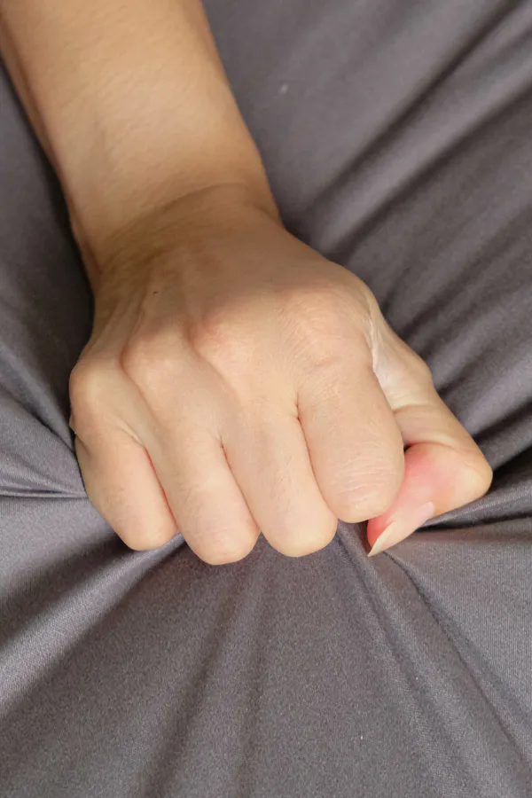 Close-up of a woman's hand grabbing a sheet, indicating sexual pleasure. Get female sexual dysfunction treatment from Thrive Family Practice & Med Spa in Statesboro.