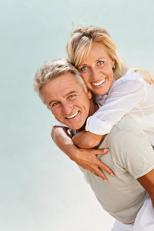A happy mature couple having fun - the husband is carrying his wife on his back. Get treatment for food allergies from Thrive Family Practice & Med Spa in Statesboro.