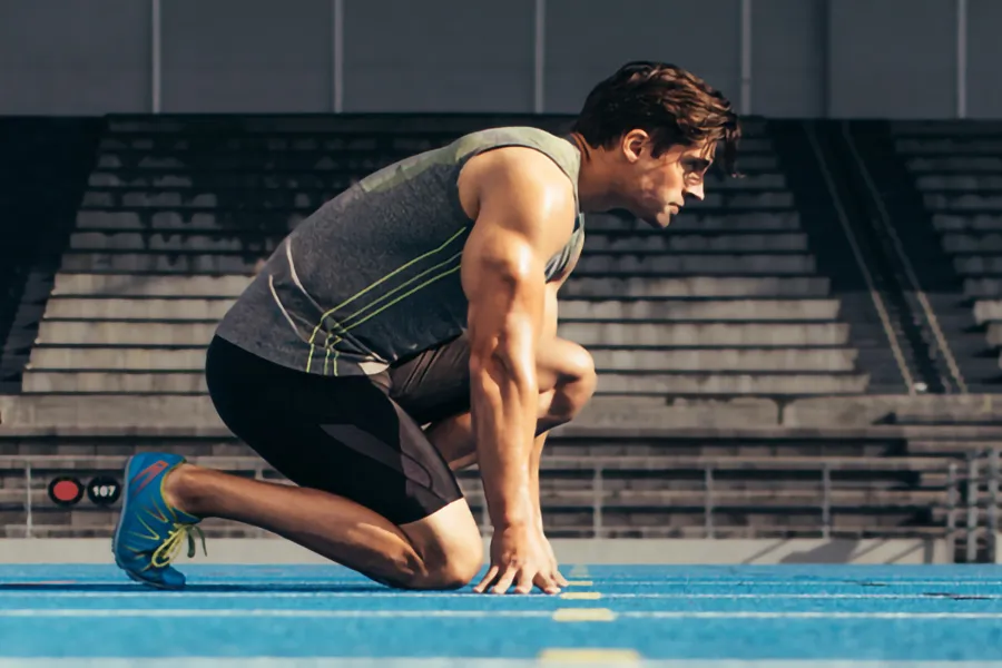 Lean-Muscle-and-Recovery-Clinic A white man kneels at the starting line on a track, determined to do his best. Get treatment for lean muscle loss and recovery from Thrive Family Practice & Med Spa in Statesboro.