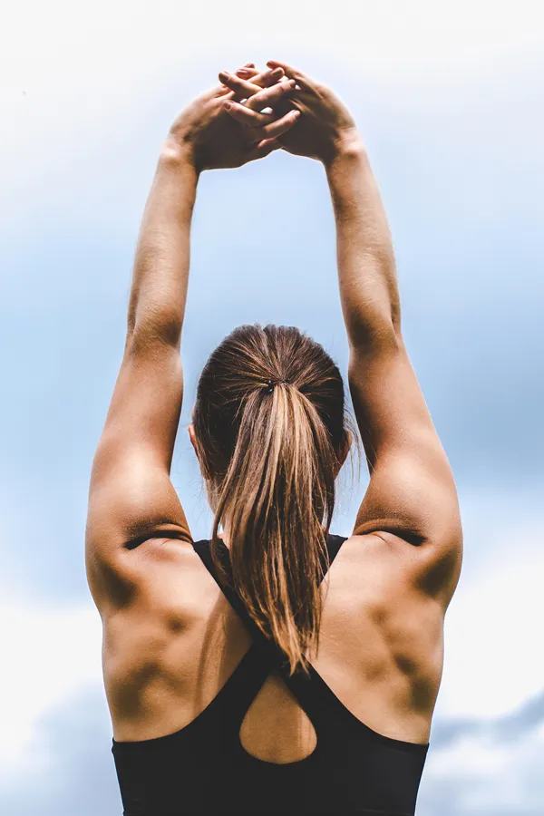 NuFlex-Muscle-Toning-Treatment A woman with exceptional muscle tone is seen from behind raising her arms to stretch. Get NuFlex Muscle Toning treatment from Thrive Family Practice & Med Spa in Statesboro.