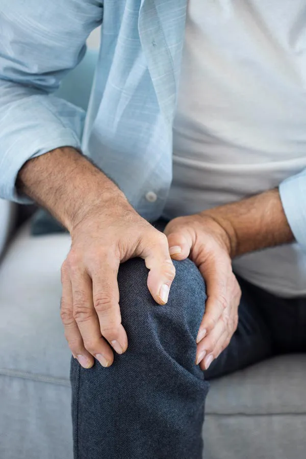 Osteoporosis-Pain A close-up of a man holding his knee while experiencing pain from osteoporosis. Get osteoporosis treatment from Thrive Family Practice & Med Spa in Statesboro.