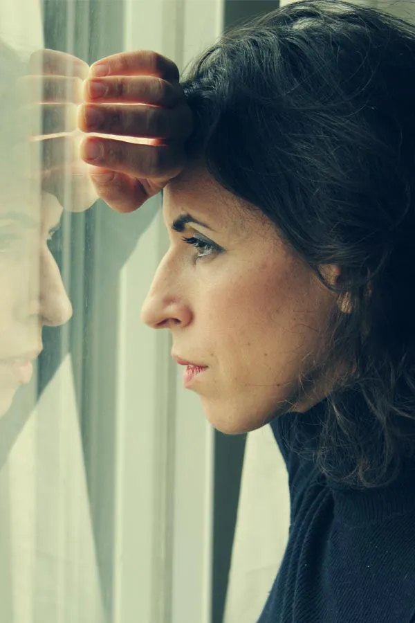PCOS-Treatment A brunette woman in a thin dark turtleneck looks out the window with a serious expression, suffering from PCOS. Get treatment for Polycistic Ovarian Syndrome/PCOS from Thrive Family Practice & Med Spa in Statesboro.