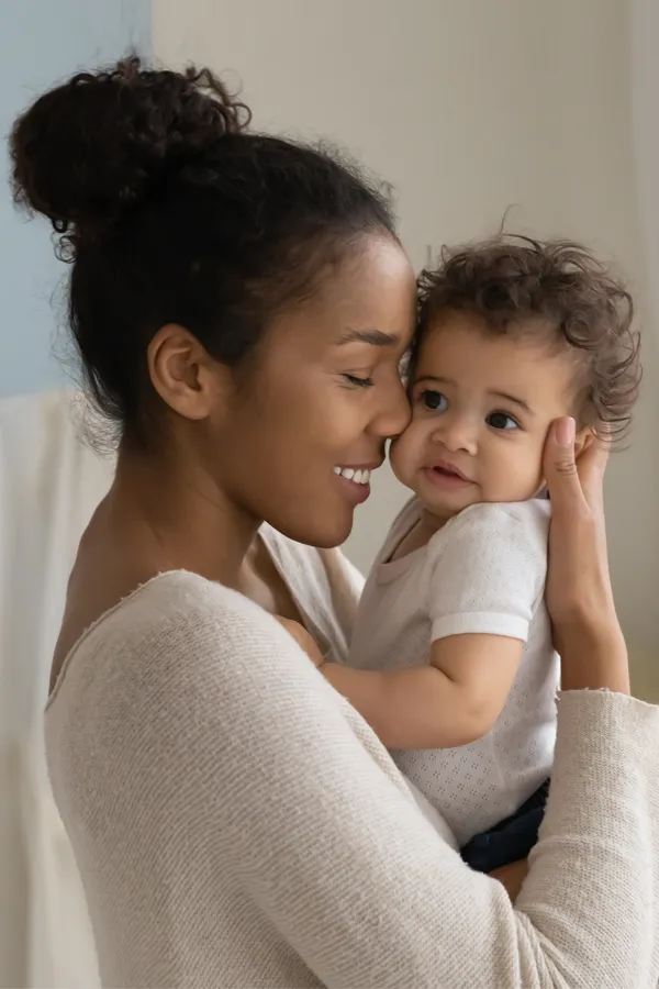 Postpartum-Hormone-Imbalance-Treatment A black woman happily touches her forehead to her infant's head. Get treatment for postpartum hormone imbalance from Thrive Family Practice & Med Spa in Statesboro.