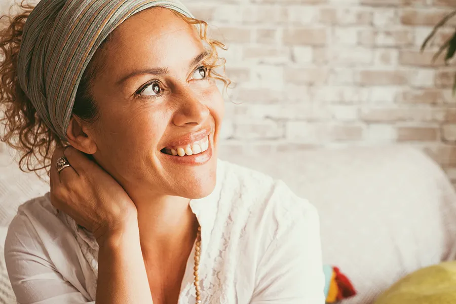 A beautiful mixed-race woman with great skin looking up and smiling. Get ProCell Microchanneling for Skin treatment from Thrive Family Practice & Med Spa in Statesboro.